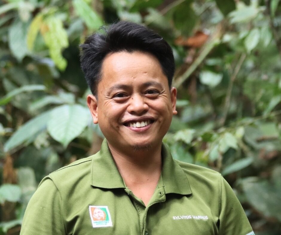 New staff member, Sylvitus, looking at the camera, holding a clipboard while in the Sabah rainforest
