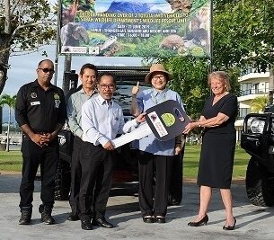 Vehicle Presentation members of Orangutan Appeal UK and the Malaysian government standing with a cut-out carboard key.