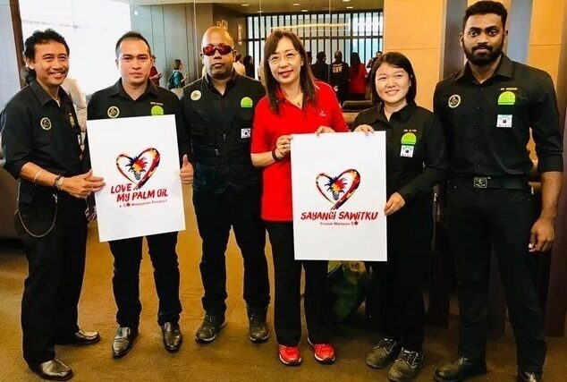 A group of people stand holding posters announcing Wildlife survey.