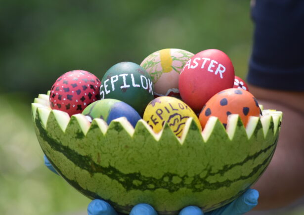 Painted Easter eggs sit inside a cut watermelon with orangutans and other animals painted on top of them.
