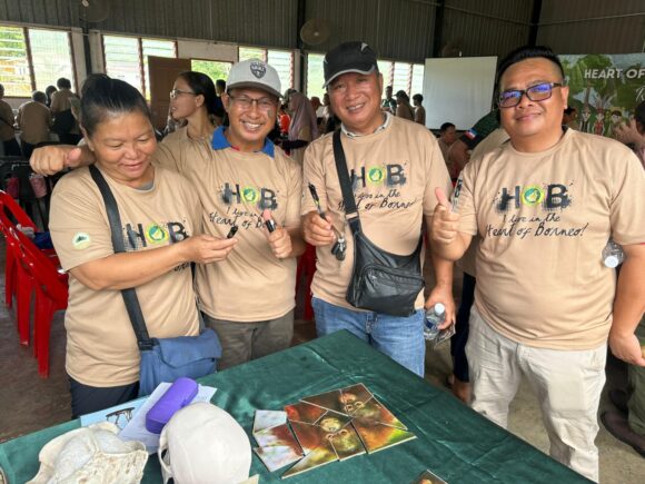Community members smiling and giving thumbs up after completing the orangutan puzzle game on the Orangutan Appeal UK stall at the Heart of Borneo event