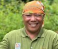 Man wearing a bright orange headband with the Orangutan Appeal UK logo across it and green leaf design.