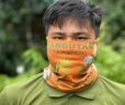 Man wearing a bright orange headband as a face covering with the Orangutan Appeal UK logo across it and green leaf design.