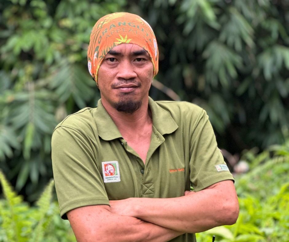 Man wearing a bright orange headband with the Orangutan Appeal UK logo across it and green leaf design.