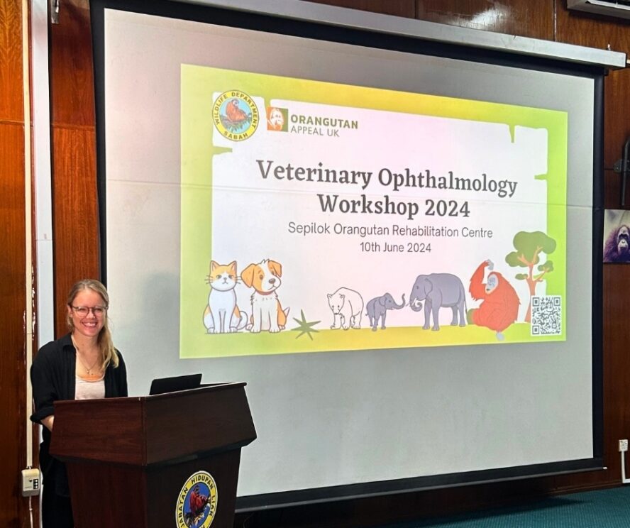 Dr Ulrike standing behind a wooden podium with a presentation board behind at Sepilok.