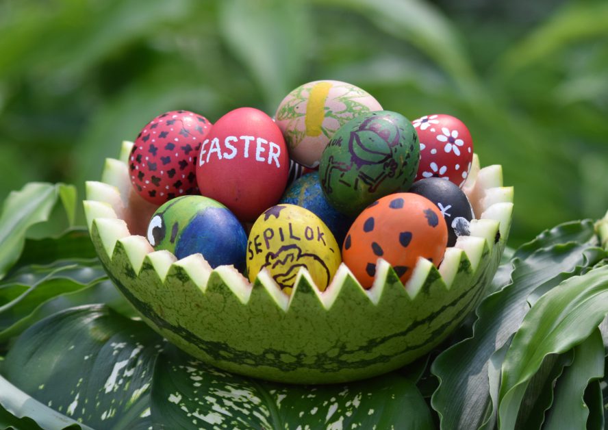 Painted Easter eggs sit inside a cut watermelon with orangutans and other animals painted on top of them.