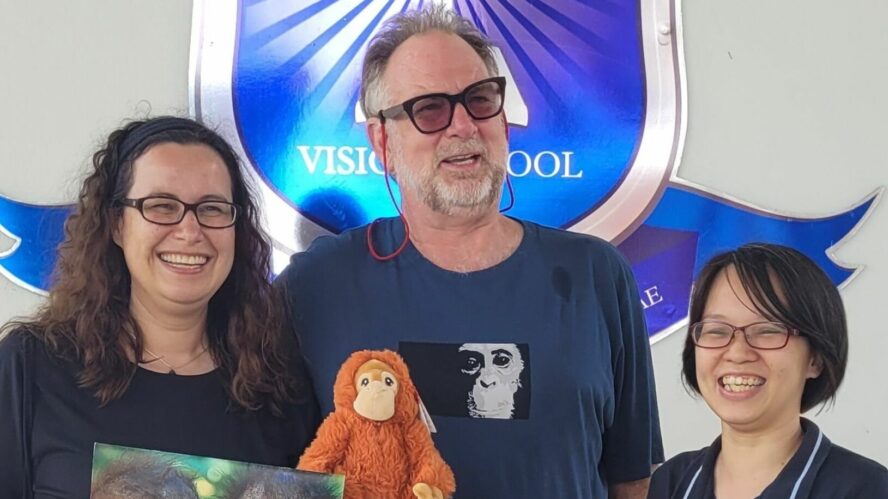 Two members of Orangutan Appeal UK post with an orangutan soft toy and certificate of thanks with Vision school representative.