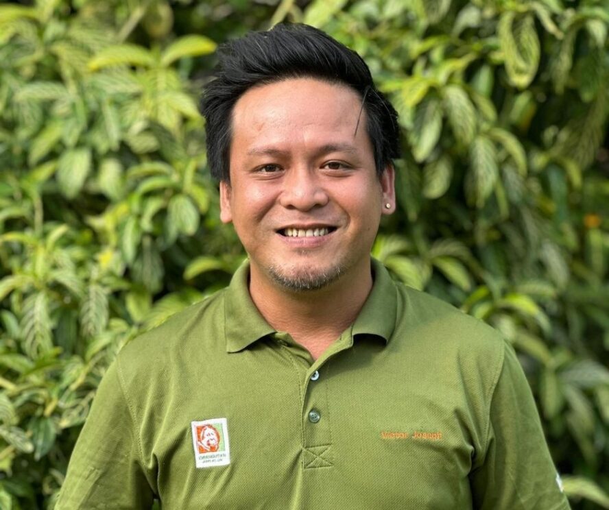 A man standing in front of a green leafy bush